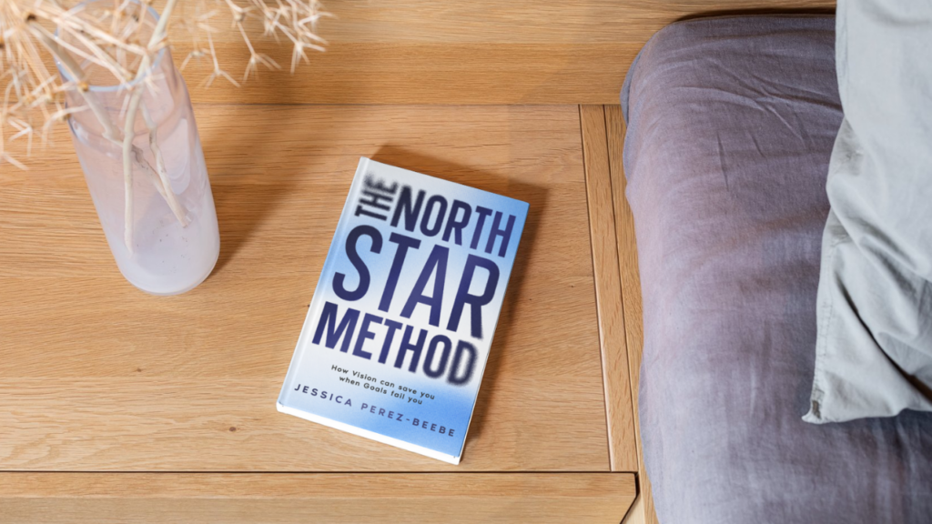 The North Star Method book on a bedside table with a notebook and highlighter, ready for reflection.